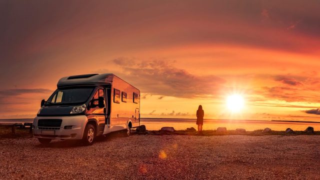 Woman at sunset with mobile home on the beach